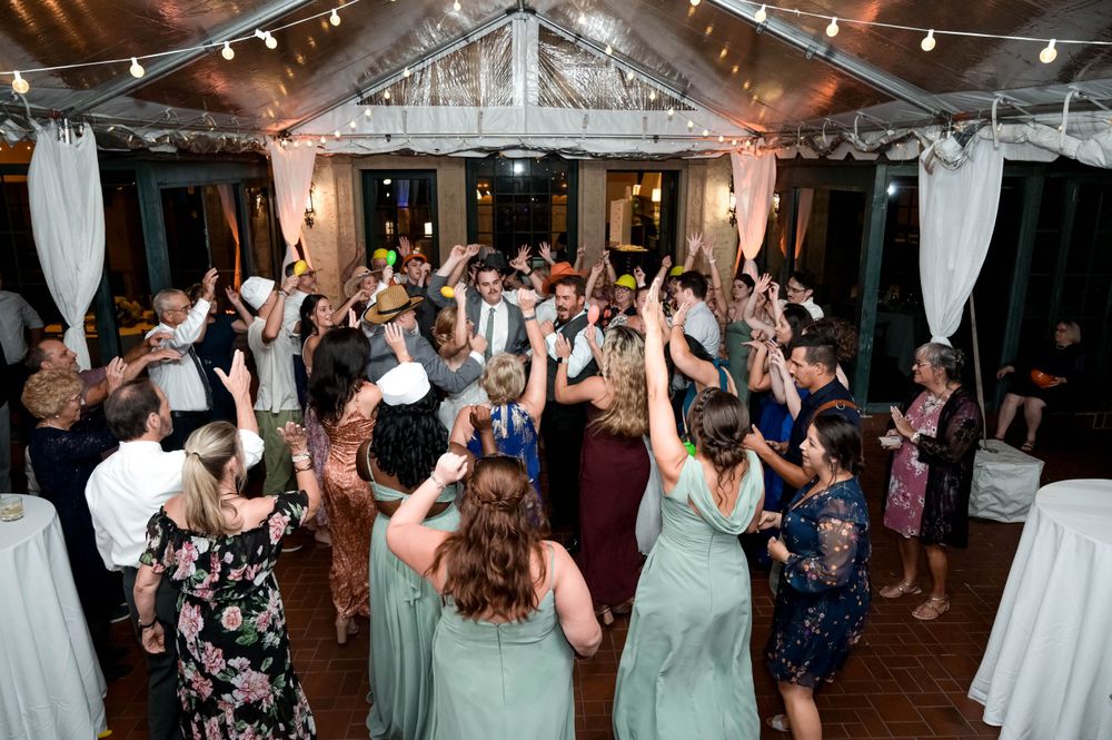 Wedding guests dancing and celebrating on a covered outdoor dance floor.