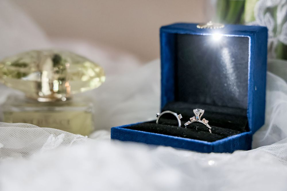 Wedding rings displayed in a navy blue velvet ring box on white fabric.