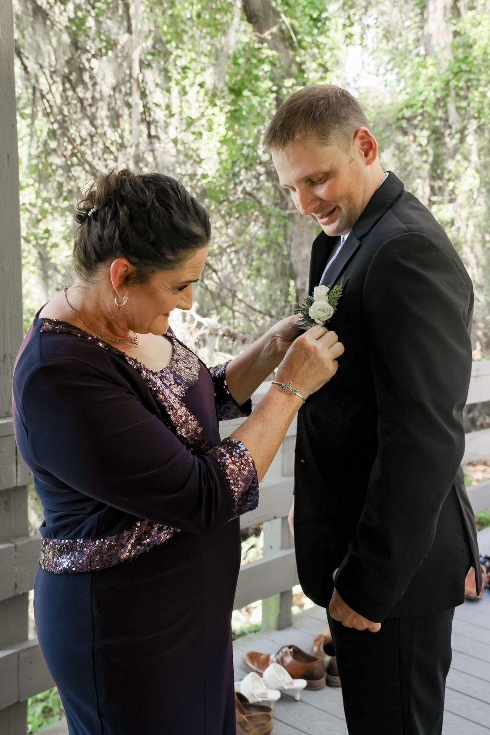 Wedding preparation moment as boutonniere is pinned on formal black suit.
