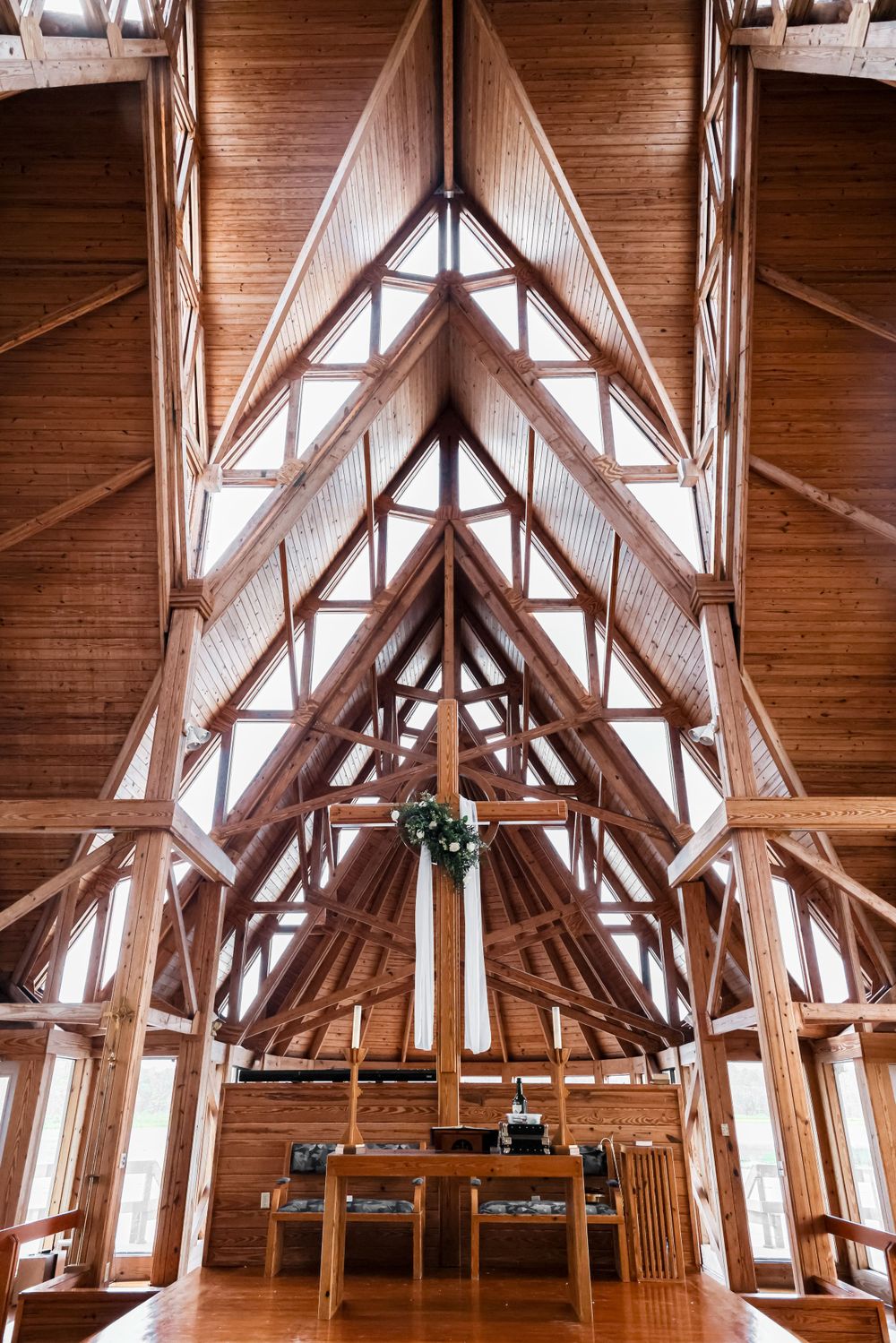 Stunning wooden cathedral ceiling with exposed beams and hanging greenery in a rustic wedding venue.