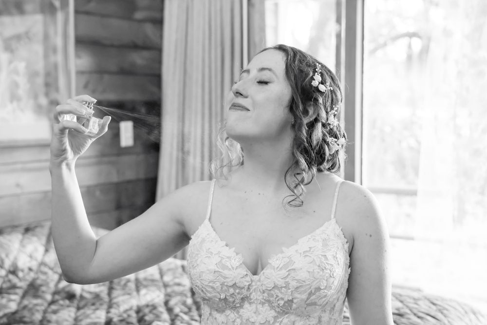 Black and white photo of someone in a wedding dress holding a perfume bottle.