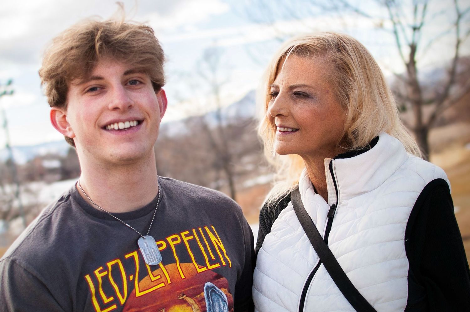 A mother and son pose with a mountain background