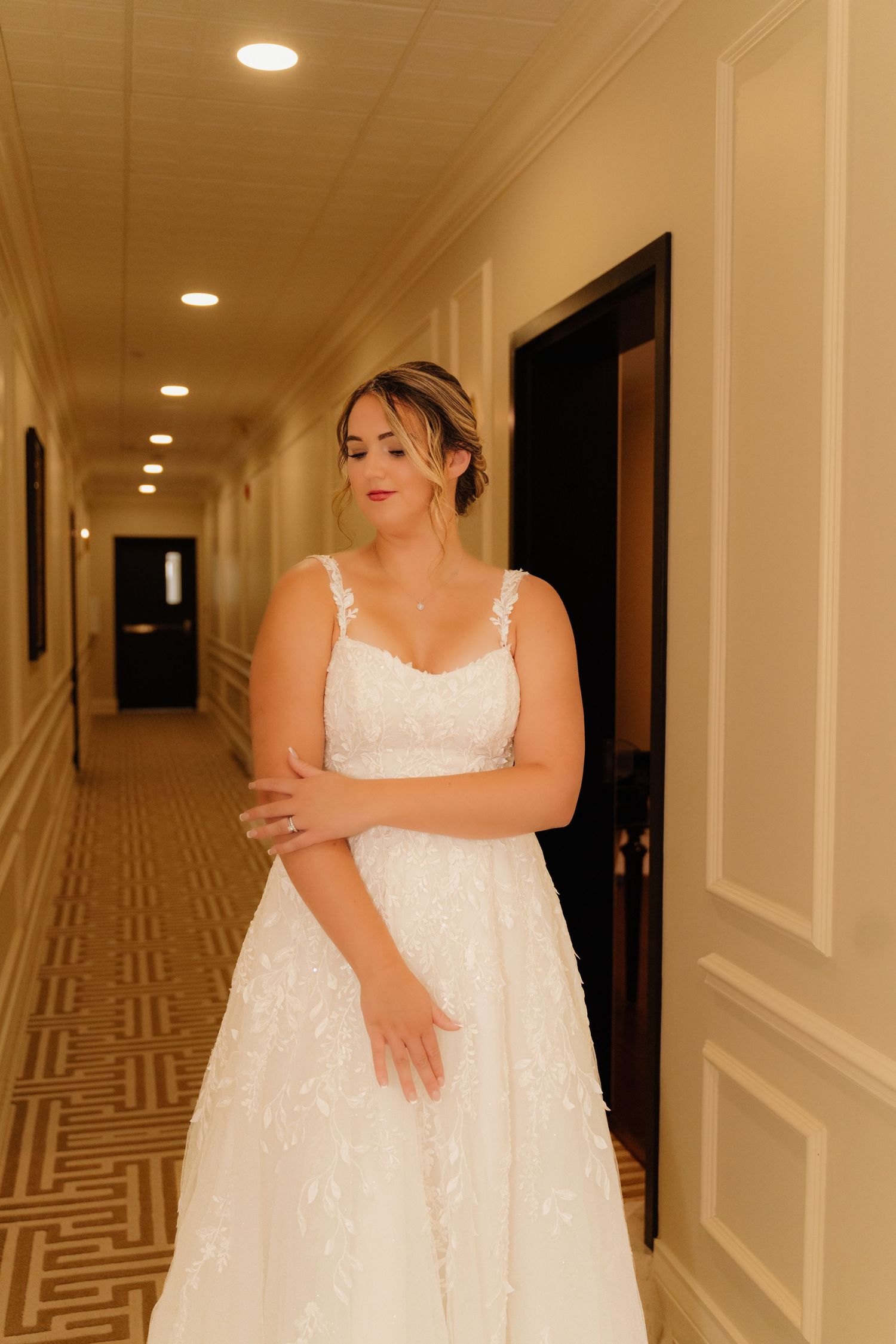 Wedding dress with lace details photographed in an elegant hotel hallway.