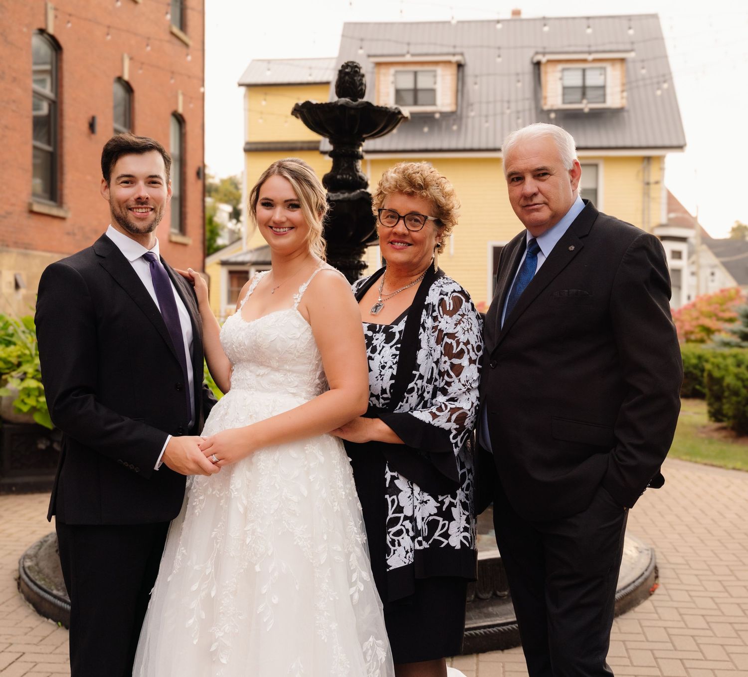 Wedding portrait of couple with family members by outdoor fountain.