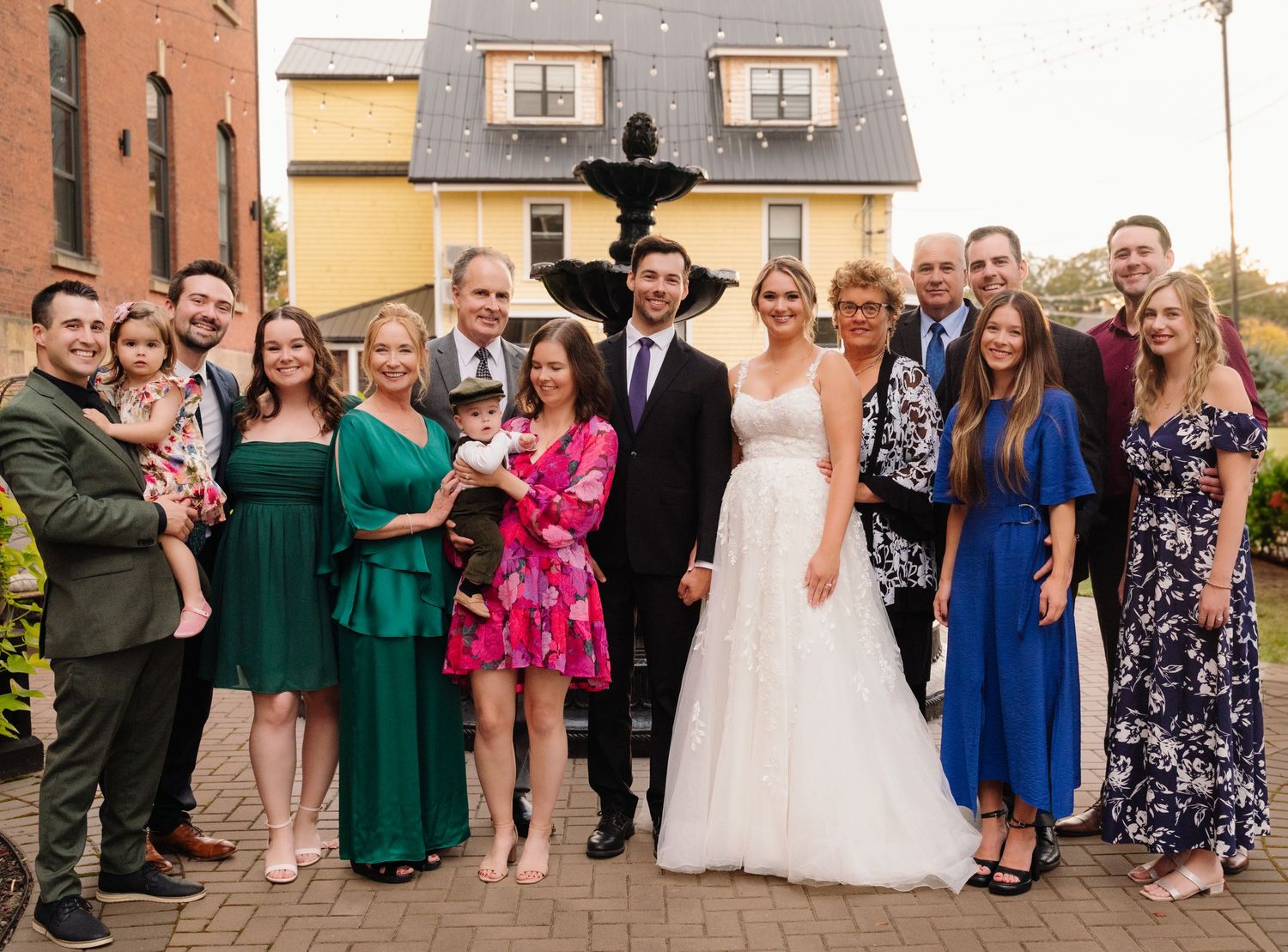 Wedding group photo with wedding party in mix of green, pink and blue formal attire.