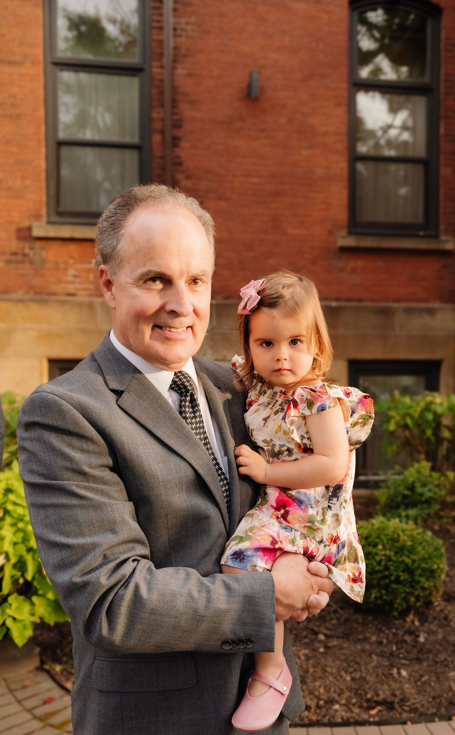 Portrait in front of brick building with flowers and architectural details.
