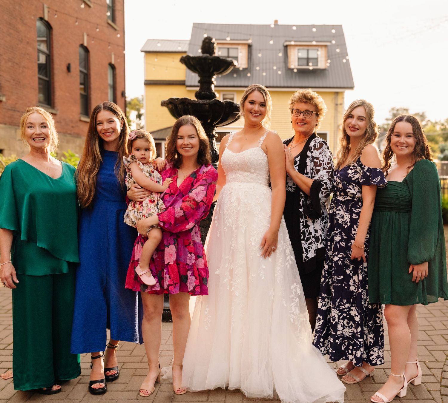 Group portrait of bride and wedding party members in coordinated formal attire.