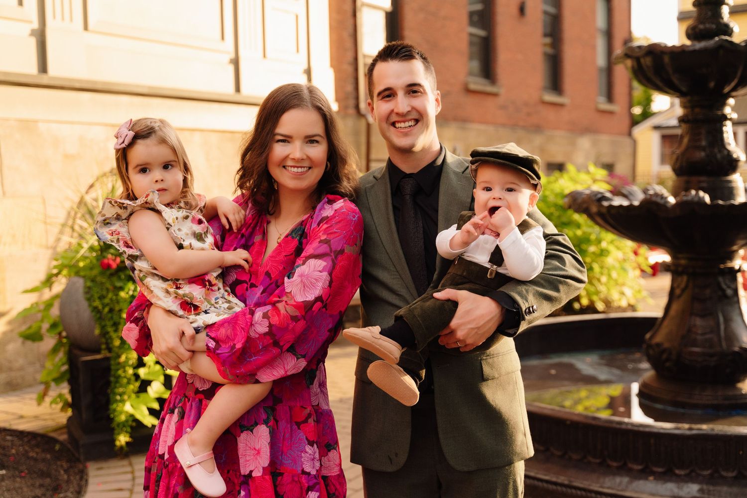 Family group poses by fountain with children in formal attire.
