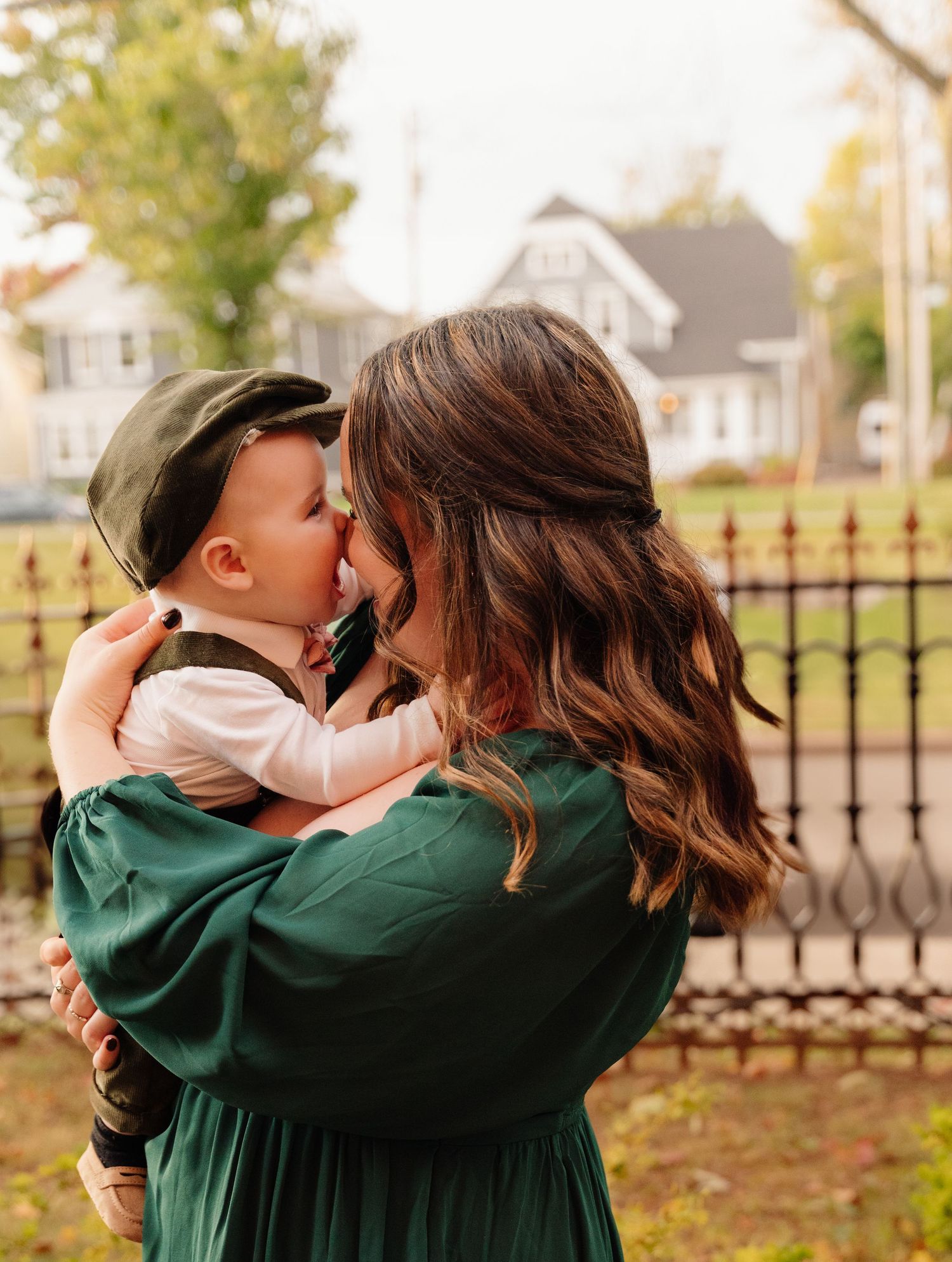 Sweet moment between parent and child in green dress outdoors during autumn.