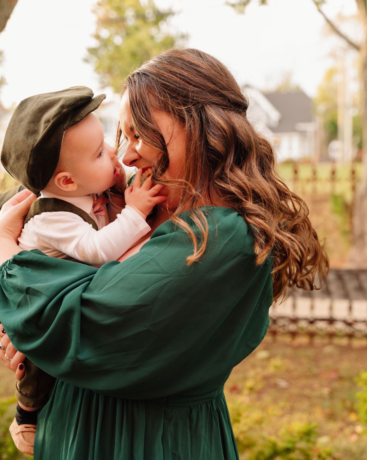 Tender moment captured between parent and child in green dress during fall photoshoot.