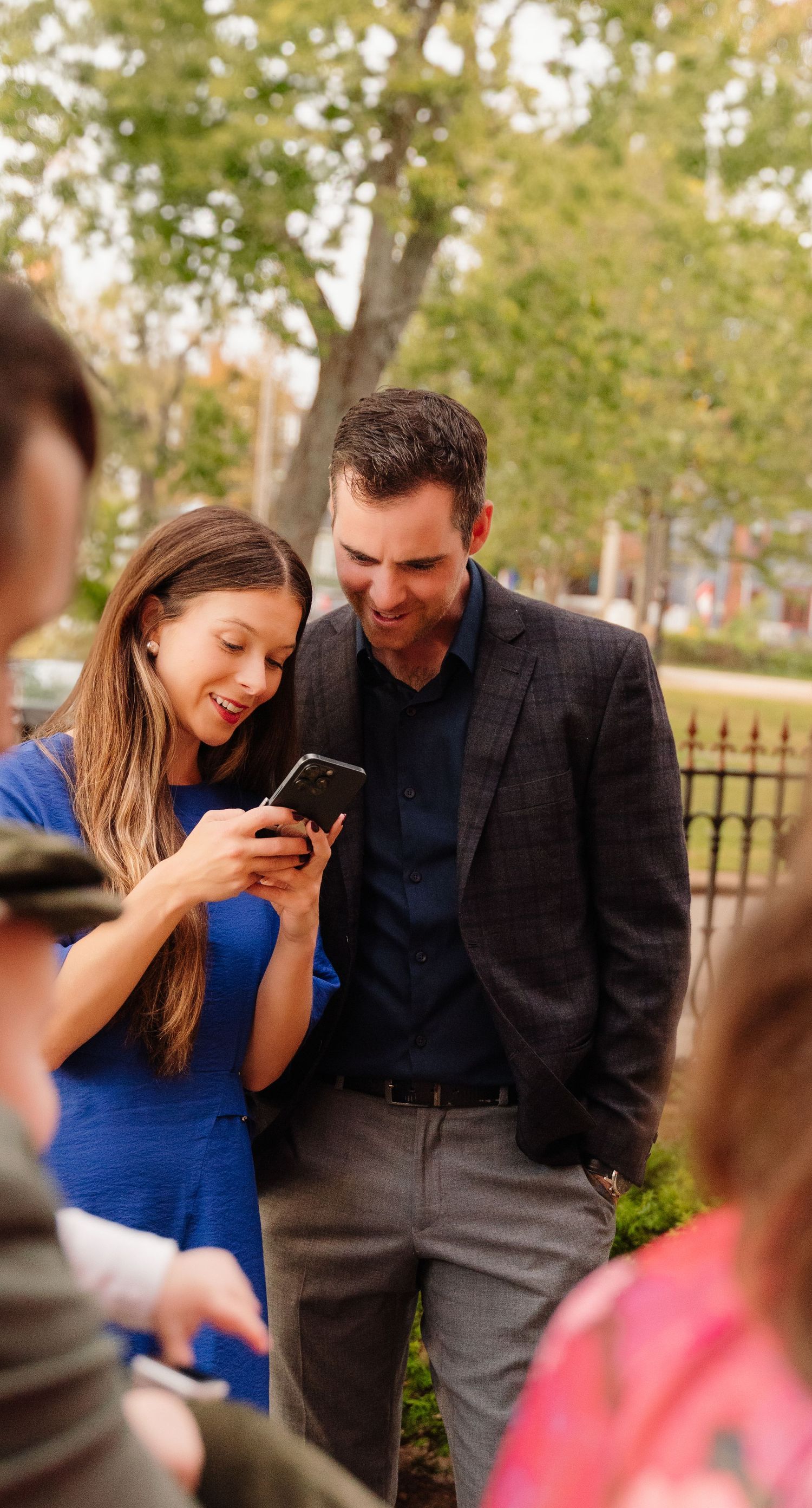 Couple sharing a laugh while looking at phone screen outdoors.