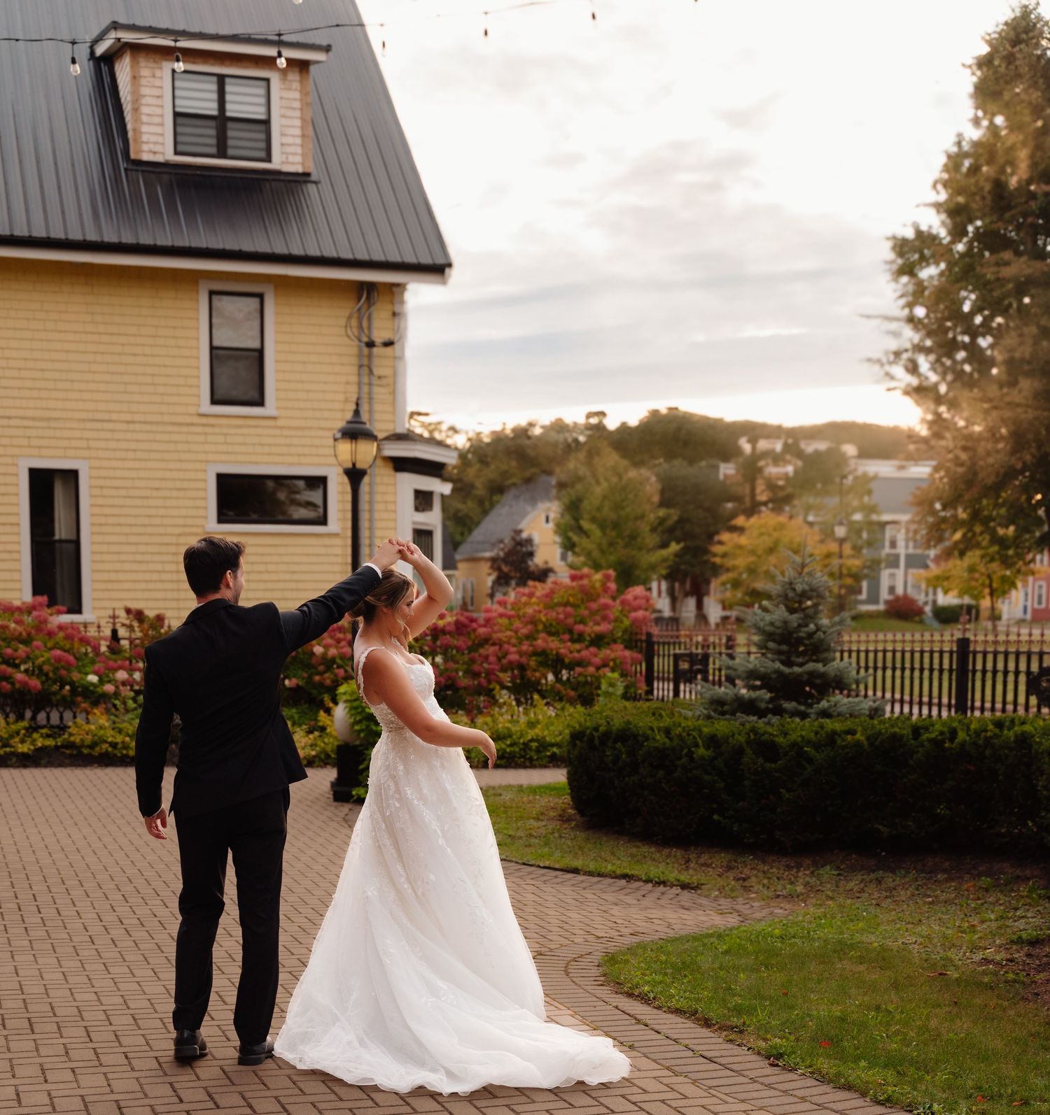 Newlyweds walking on brick path near yellow house with autumn scenery. The sydney boutique hotel