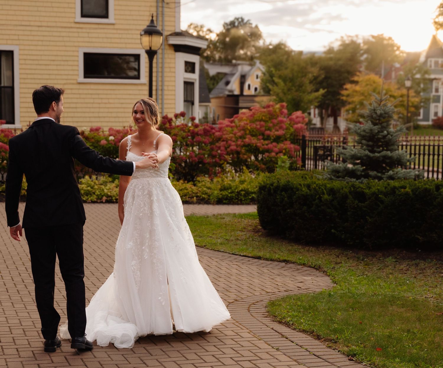A couple shares a romantic moment on brick pathway surrounded by fall foliage.