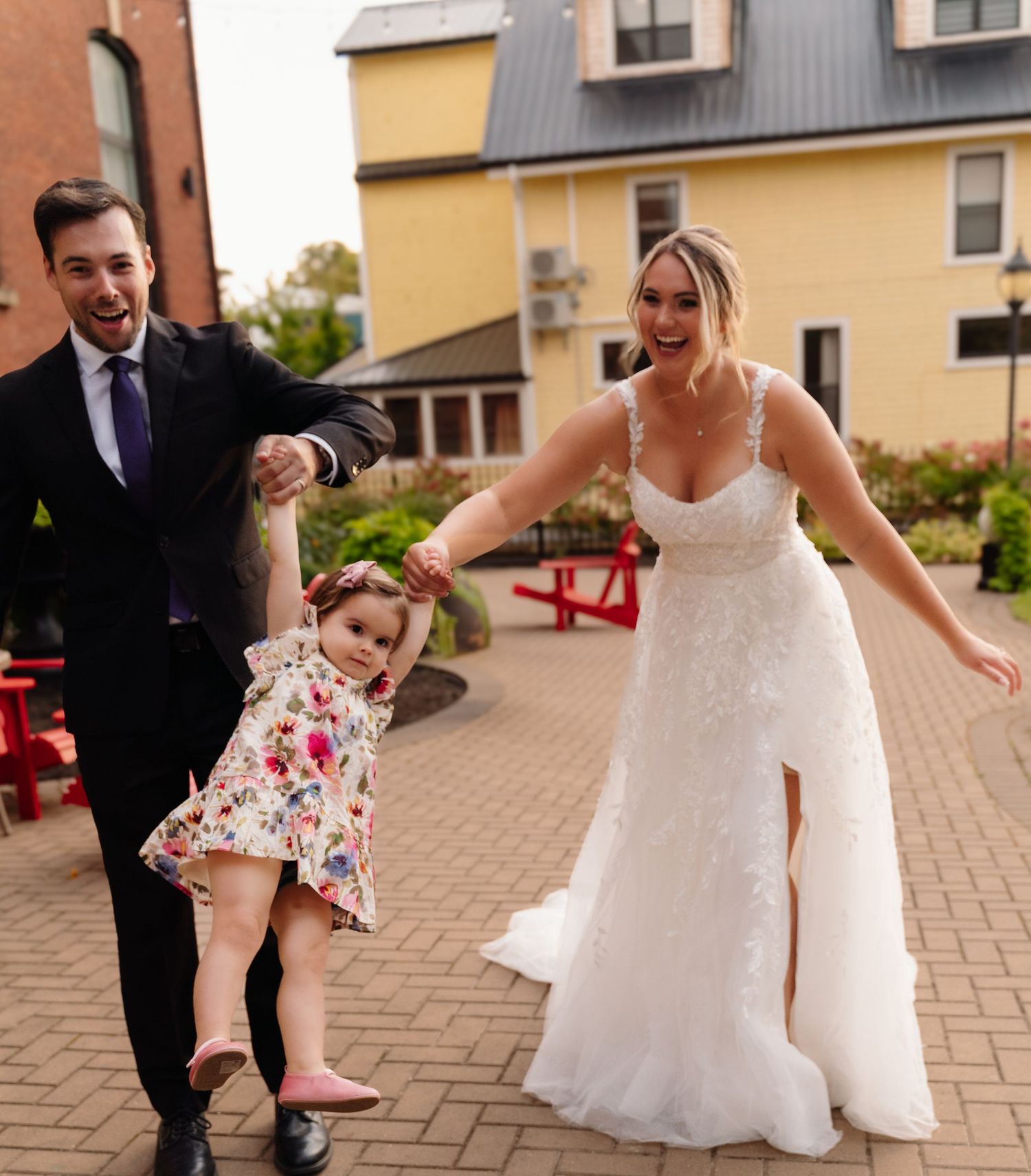A family enjoying a playful moment on brick pathway with red and yellow buildings in background.