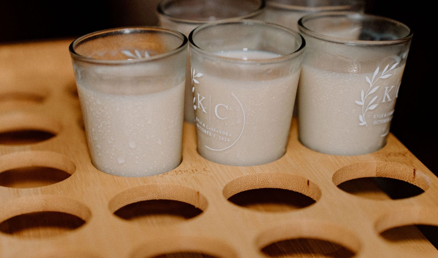 Three glasses of creamy beige cocktails arranged in a wooden holder.
