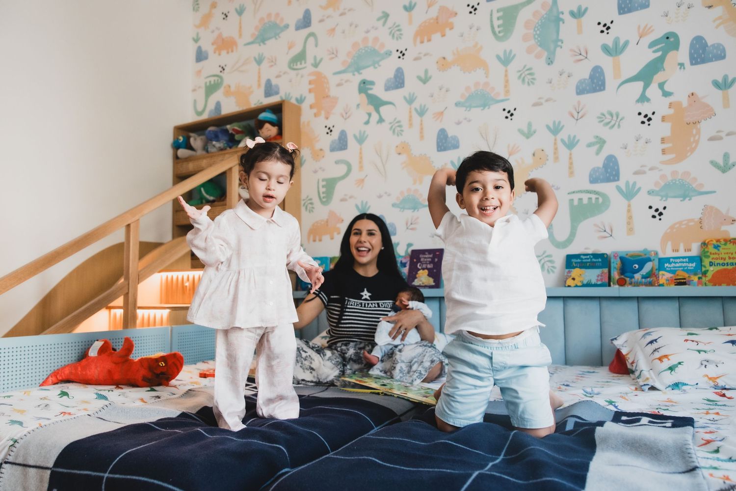 Children jumping on bed while playing in colorfully decorated bedroom.