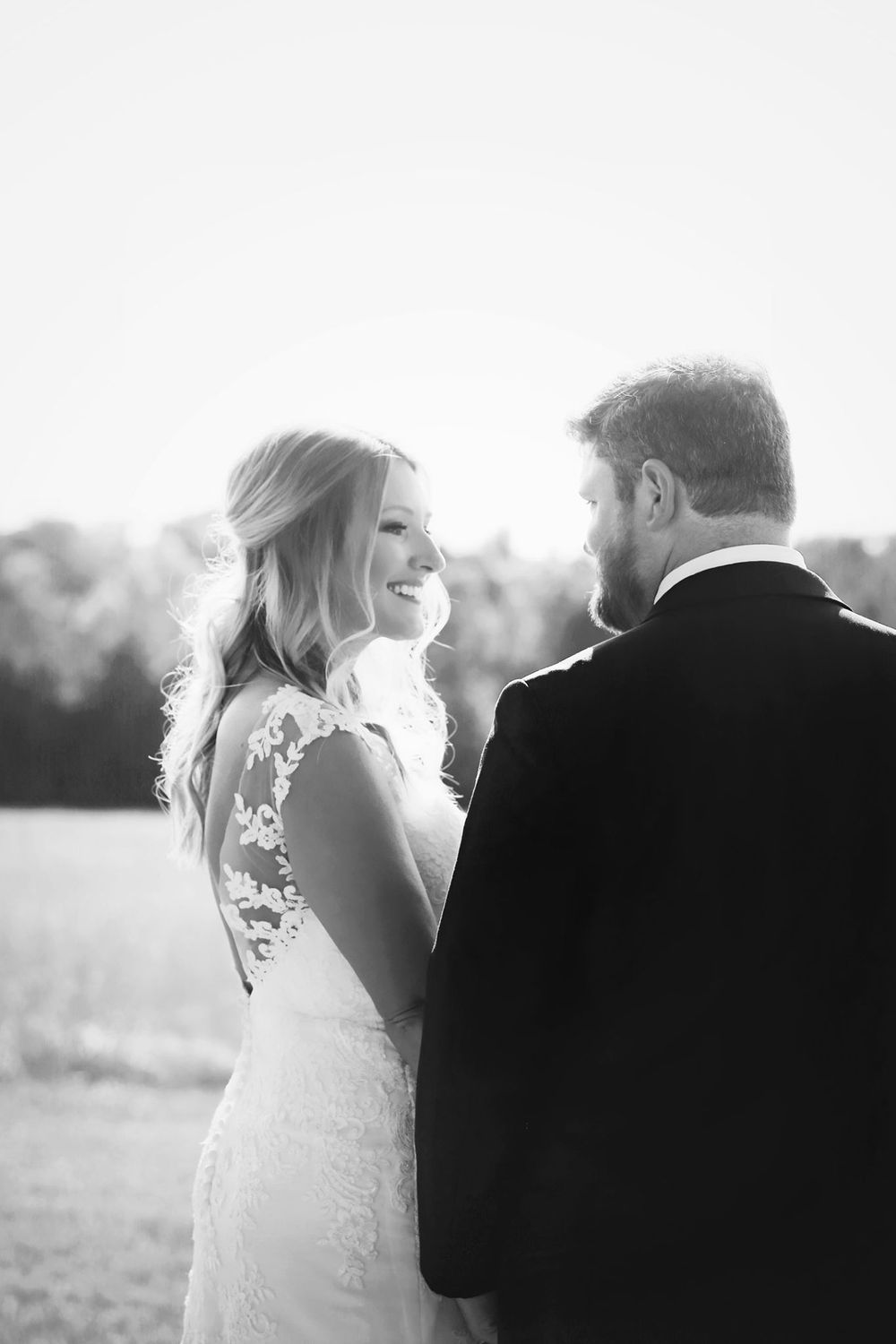 A romantic black and white portrait of newlyweds sharing an intimate moment outdoors.