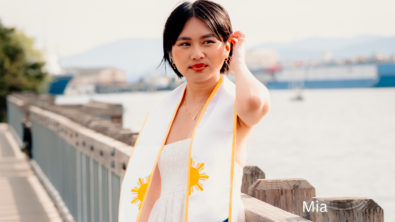 Person in white shirt with yellow scarf standing by waterfront railing on sunny day.