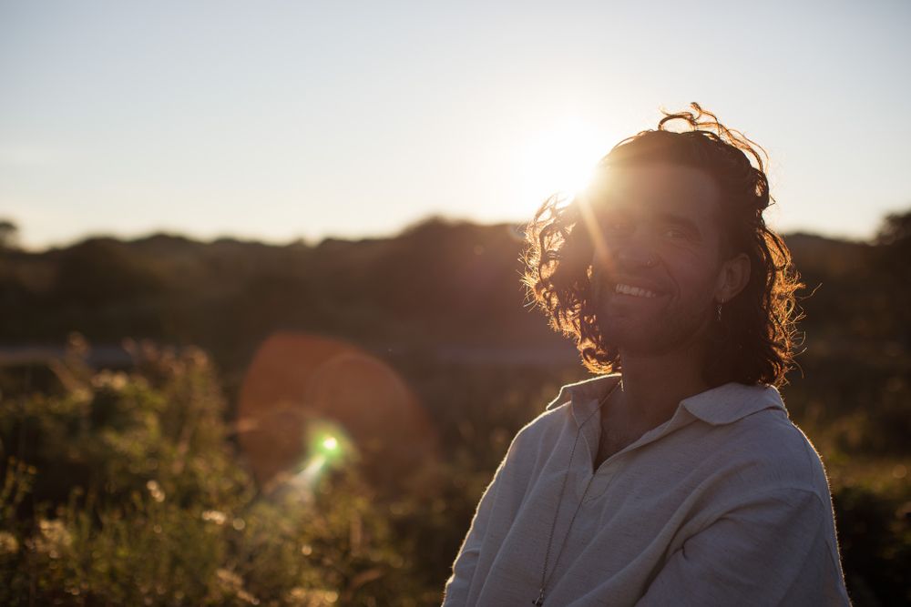 Person in white clothing silhouetted against golden sunset light.
