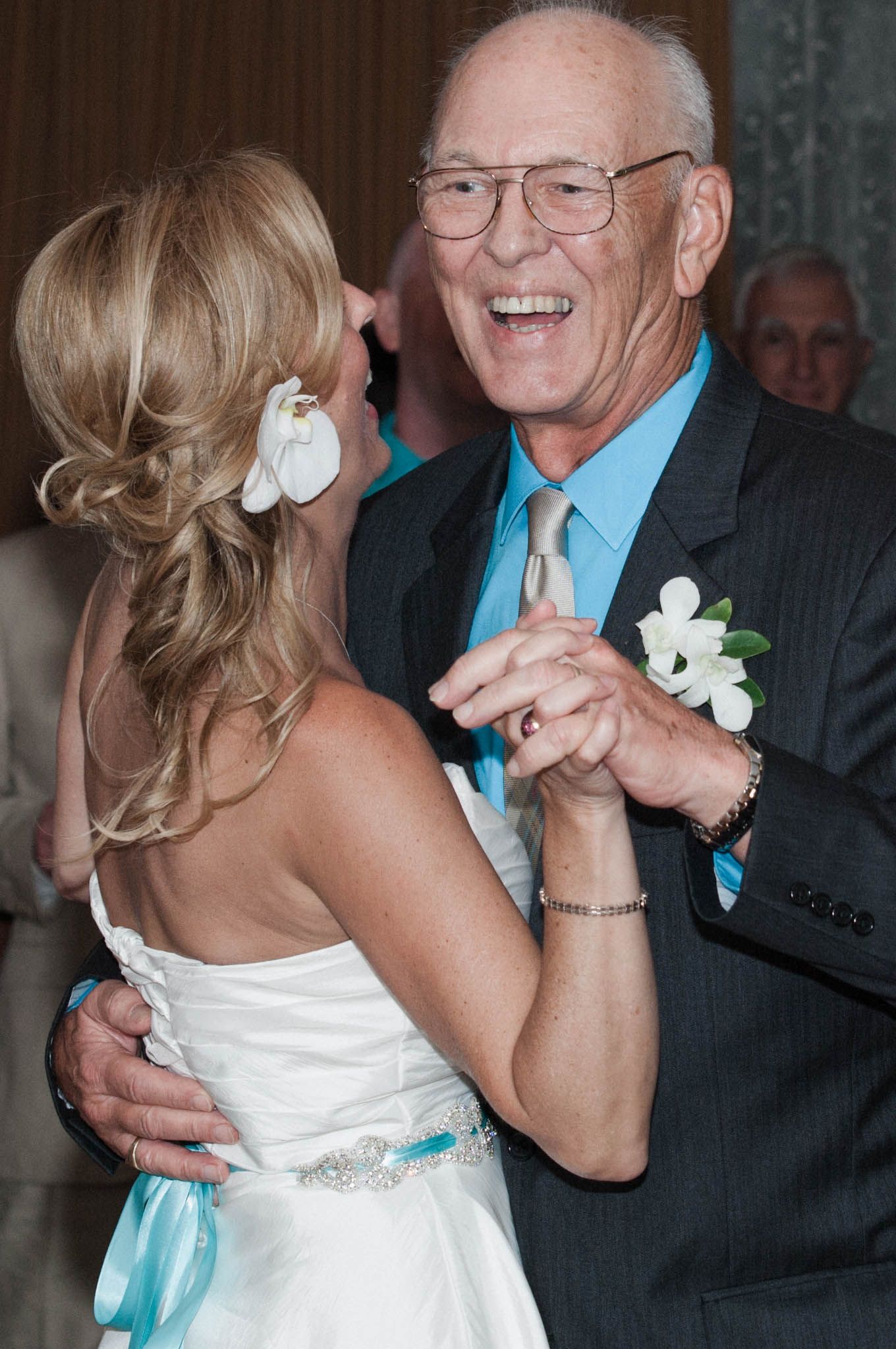 A tender dance moment at a wedding reception with turquoise and white formal attire.
