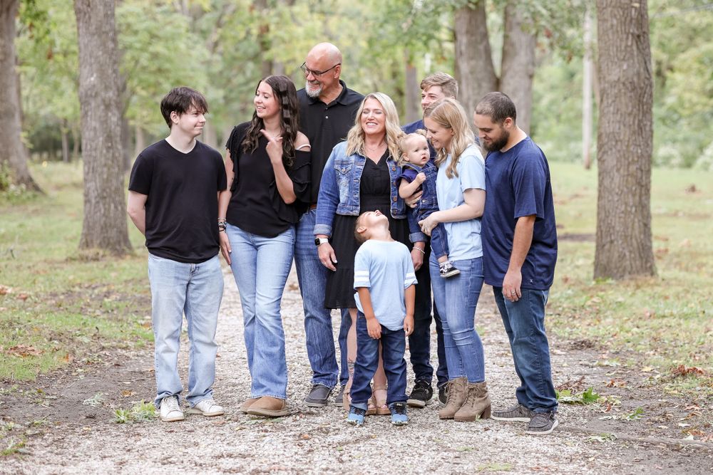 Candid moment of a family of 9 smiling and laughing together on a trail surrounded by trees
