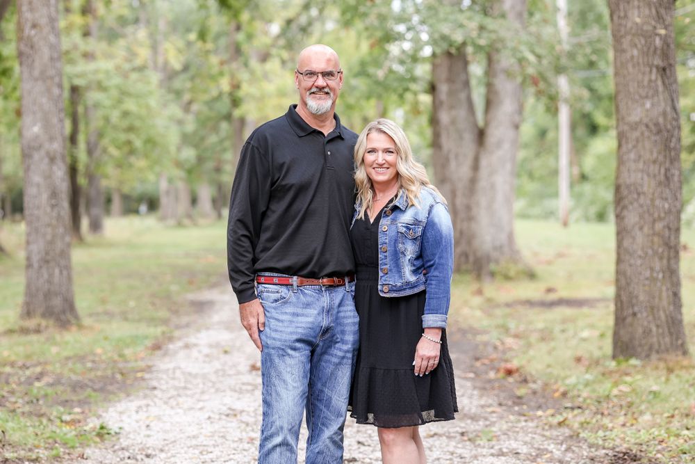Couple stands together on a trail while smiling