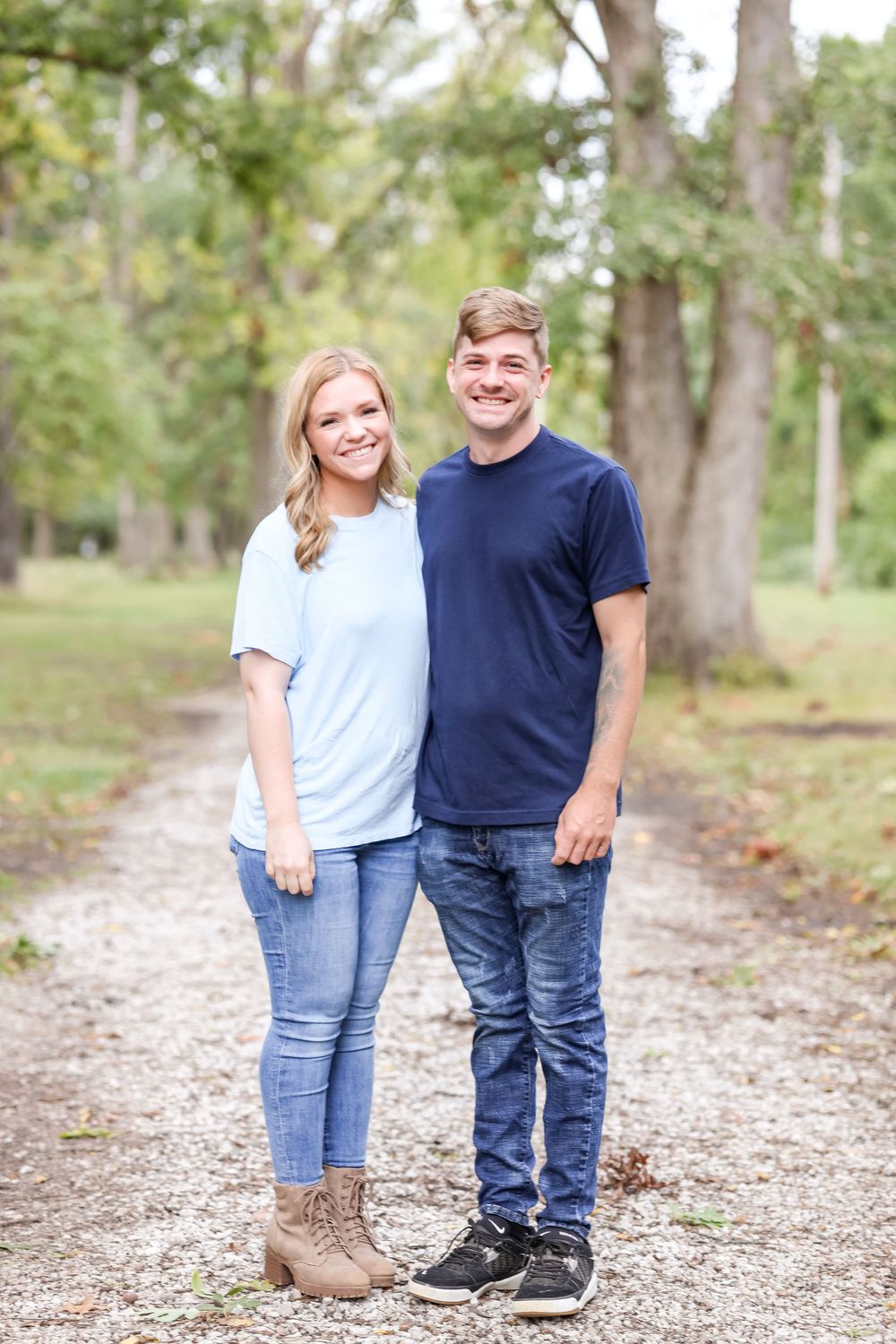 Grown siblings stand together on a tree-lined trail