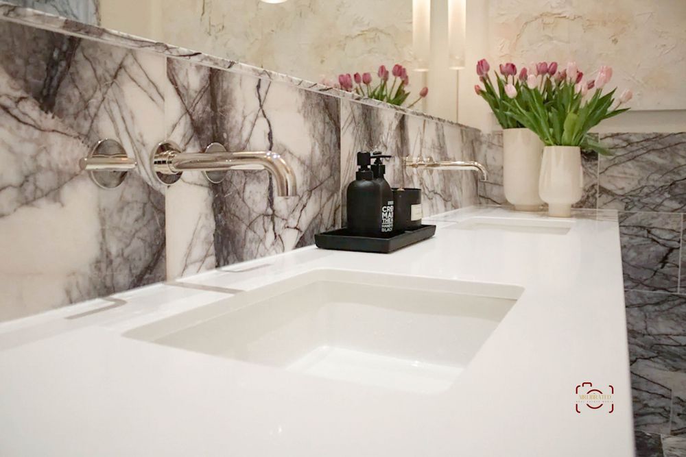 White quartz double vanity with marble backsplash and fresh tulip arrangement.