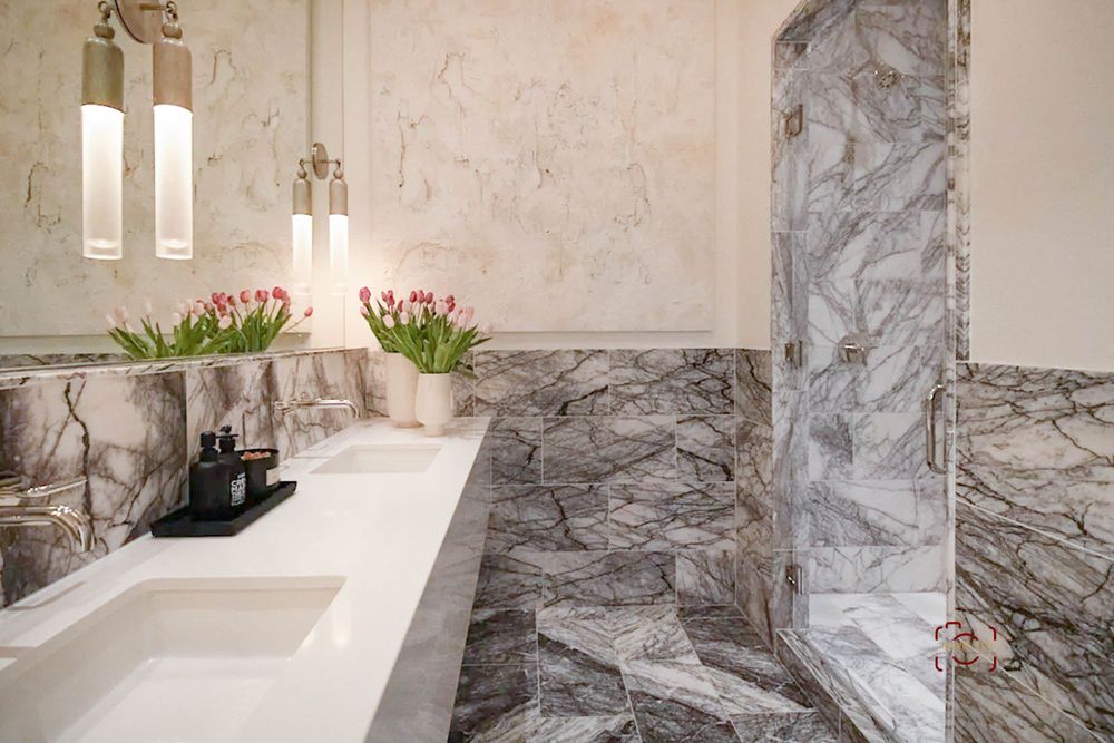 Luxury marble bathroom with white countertop, tulips, and elegant lighting fixtures.