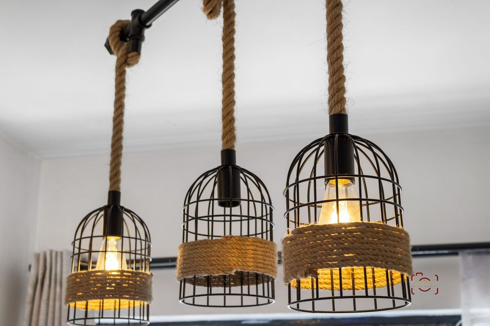 Three rustic pendant lights with metal cage shades and rope cords hang from a white ceiling, creating industrial farmhouse decor.