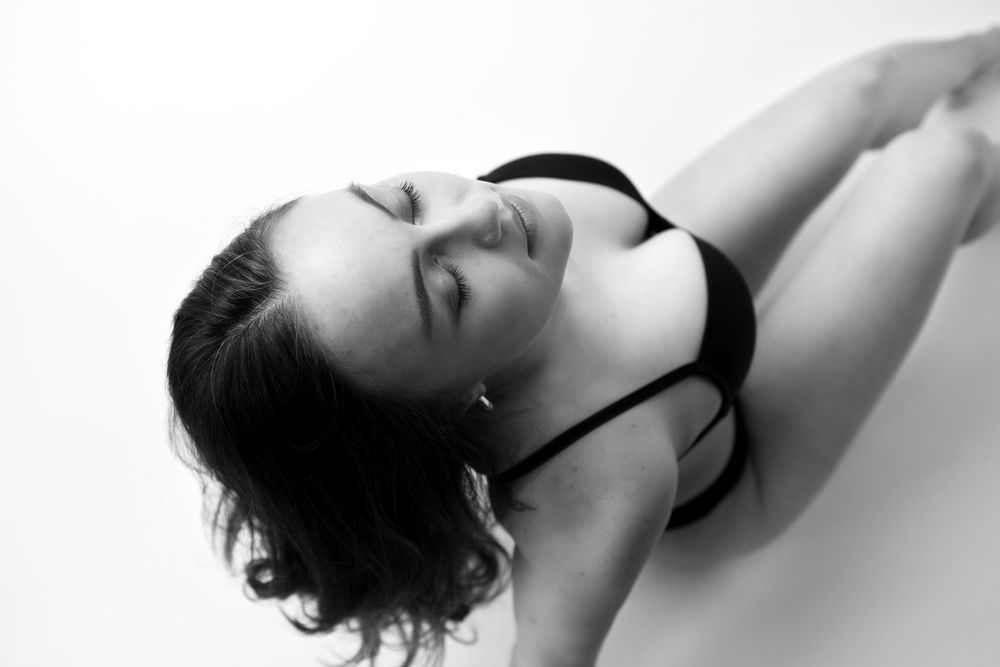 Black and white boudoir portrait in studio photo sitting with legs bent taken from behind and above.