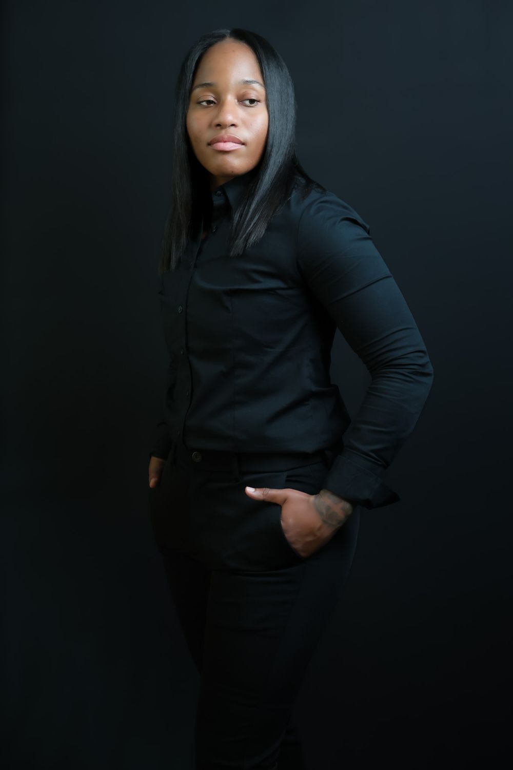 Person in black ensemble creates dynamic silhouette against dark backdrop.