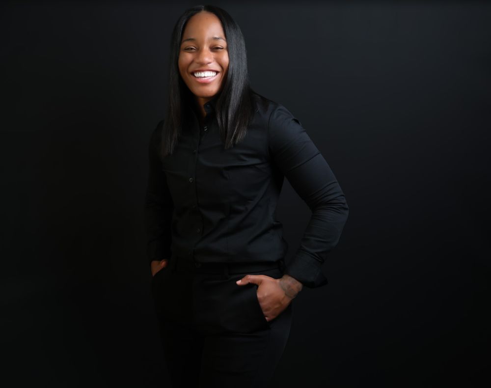 Expressive portrait against dark background with subject in black clothing.