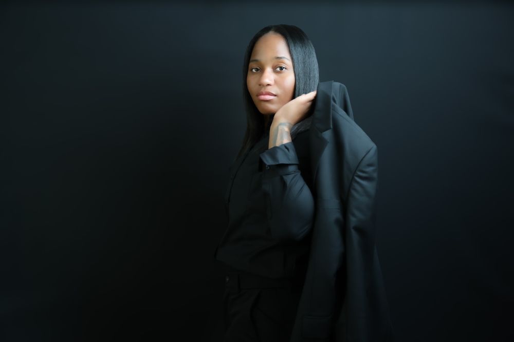 Moody artistic portrait with figure in dark clothing against black backdrop.