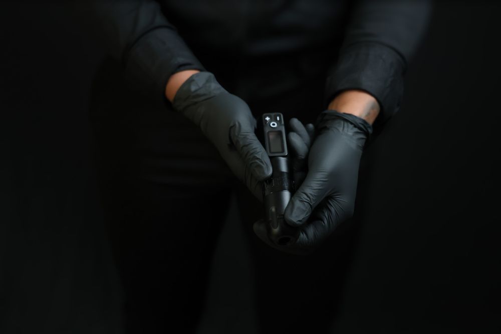 Close-up of hands wearing black leather gloves against dark background.