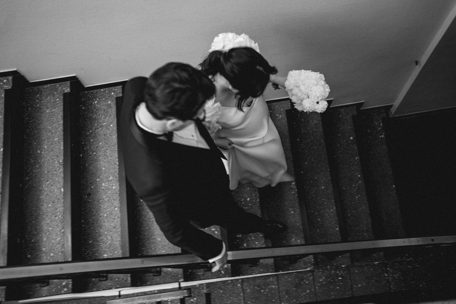 A wedding reflection captured in an ornate white mirror above an antique table.