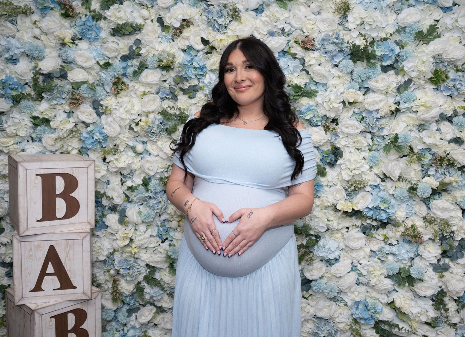 Baby shower with wooden letter blocks and elegant floral wall setting.
