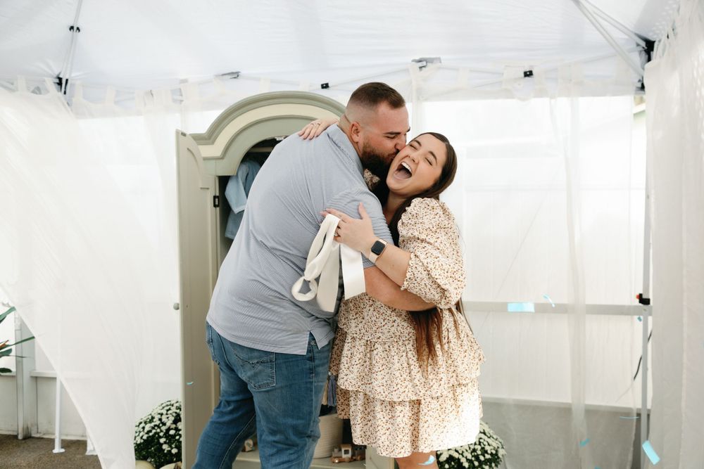 Joyful couple hugging and laughing after baby boy gender reveal celebration outdoors.