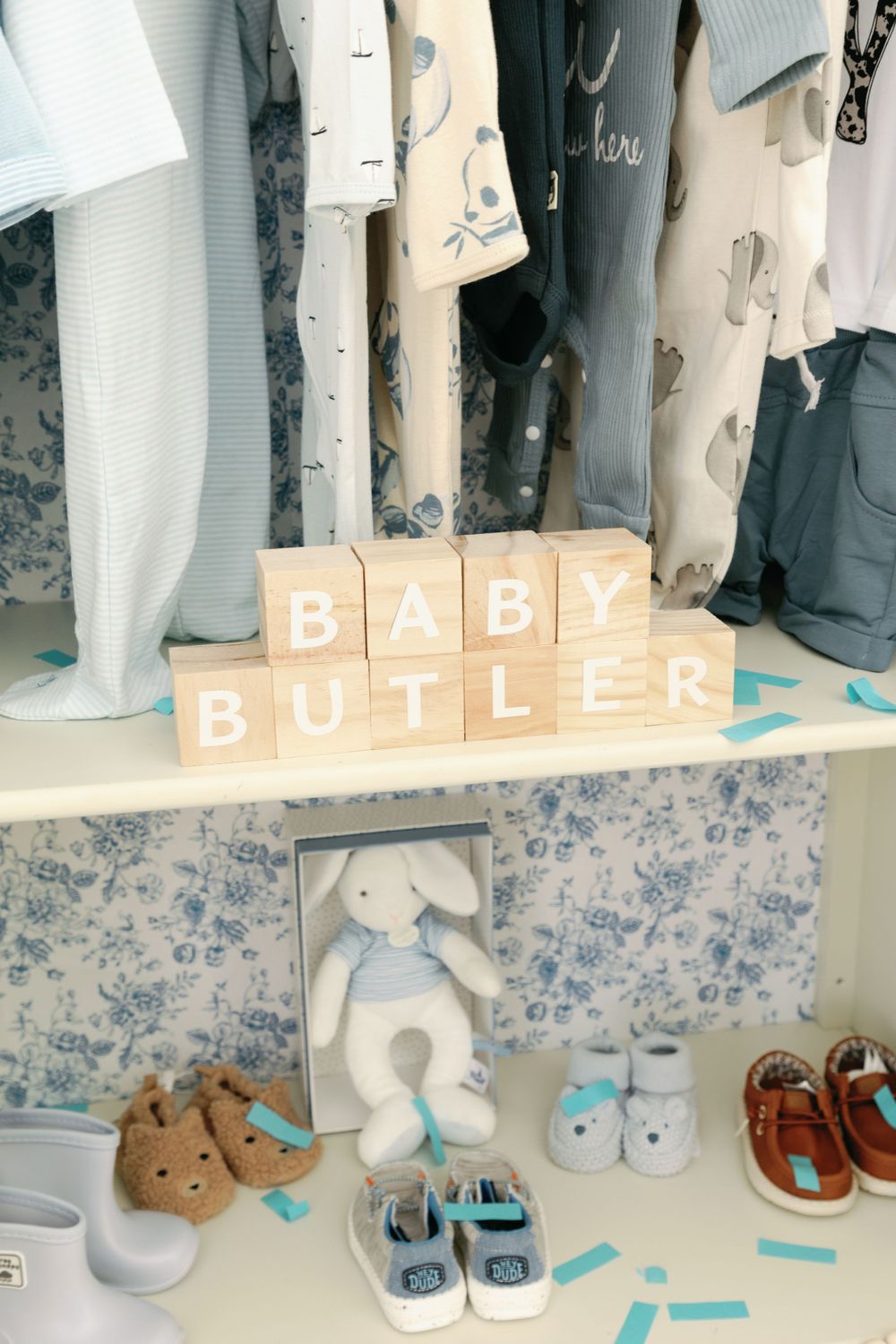 Baby Butler wooden letter blocks displayed with shoes and stuffed bunny in nursery armoire.