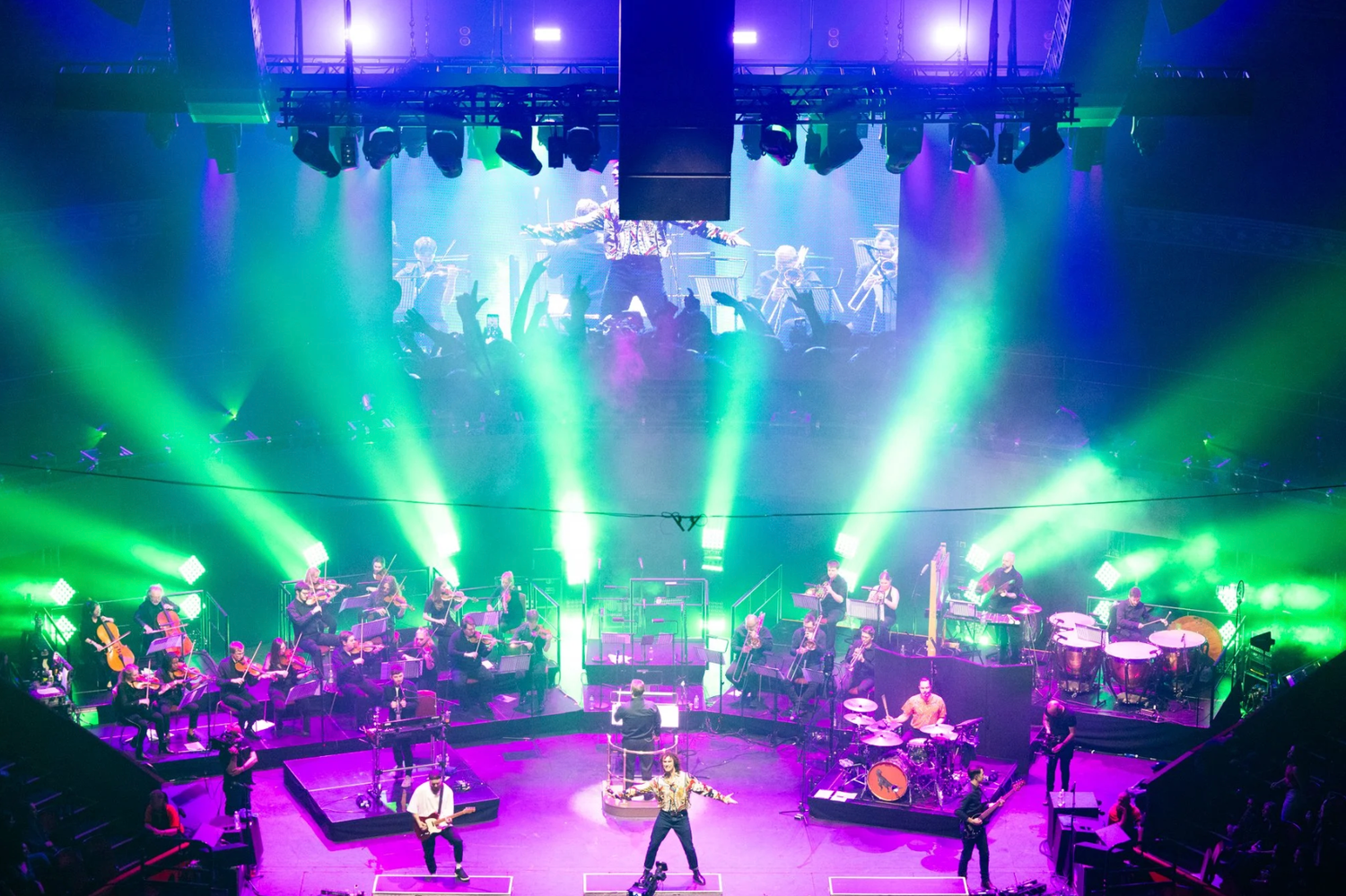 Concert stage illuminated with vibrant blue and green lights creating an atmospheric performance environment.
