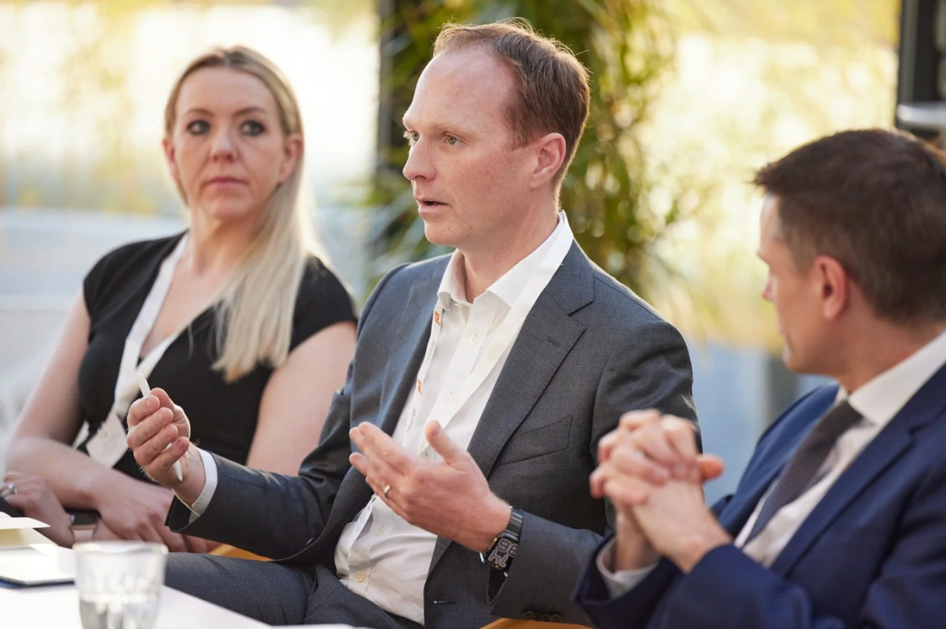 Business professionals taking notes and participating in a corporate meeting discussion at a conference table.