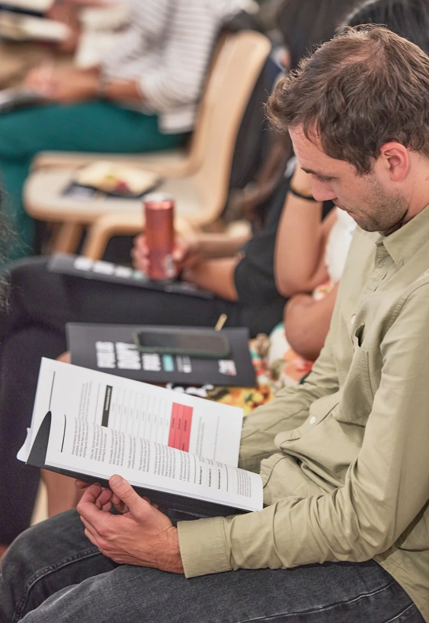 A person in a light colored shirt reviews paperwork while sitting in a casual indoor setting.
