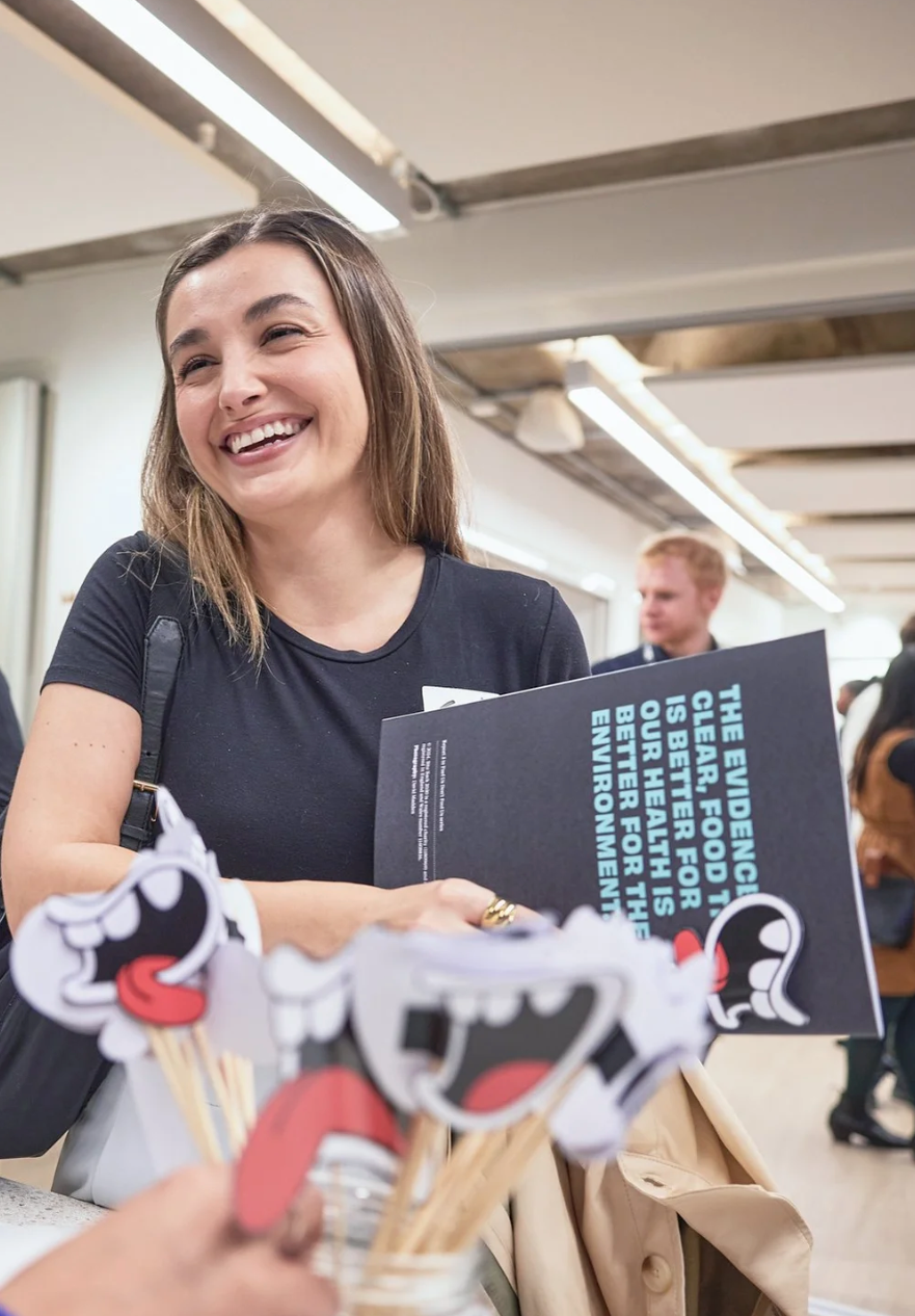 A sequence of images shows someone in a black shirt laughing while interacting with a puppet and book in a bright indoor setting.