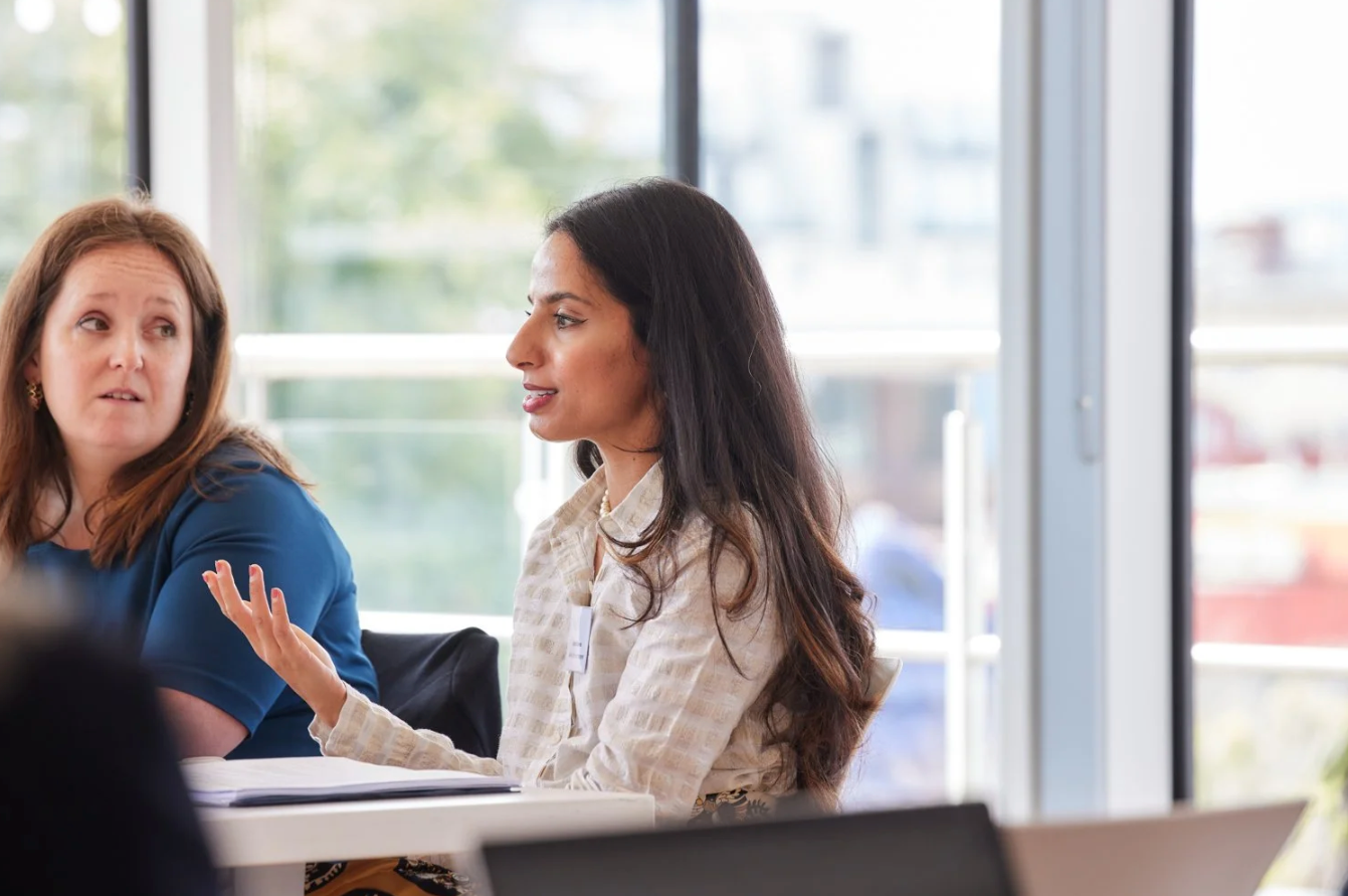 Diverse group of professionals engage in animated discussion during a bright office meeting.