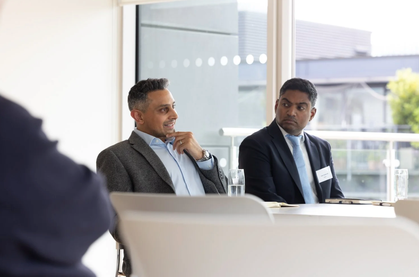 Business professionals sitting at conference table during corporate meeting or panel discussion.