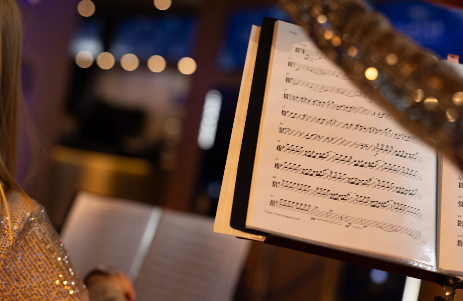 Sheet music pages and musical notes shown in soft focus with warm bokeh lights glowing in the background.