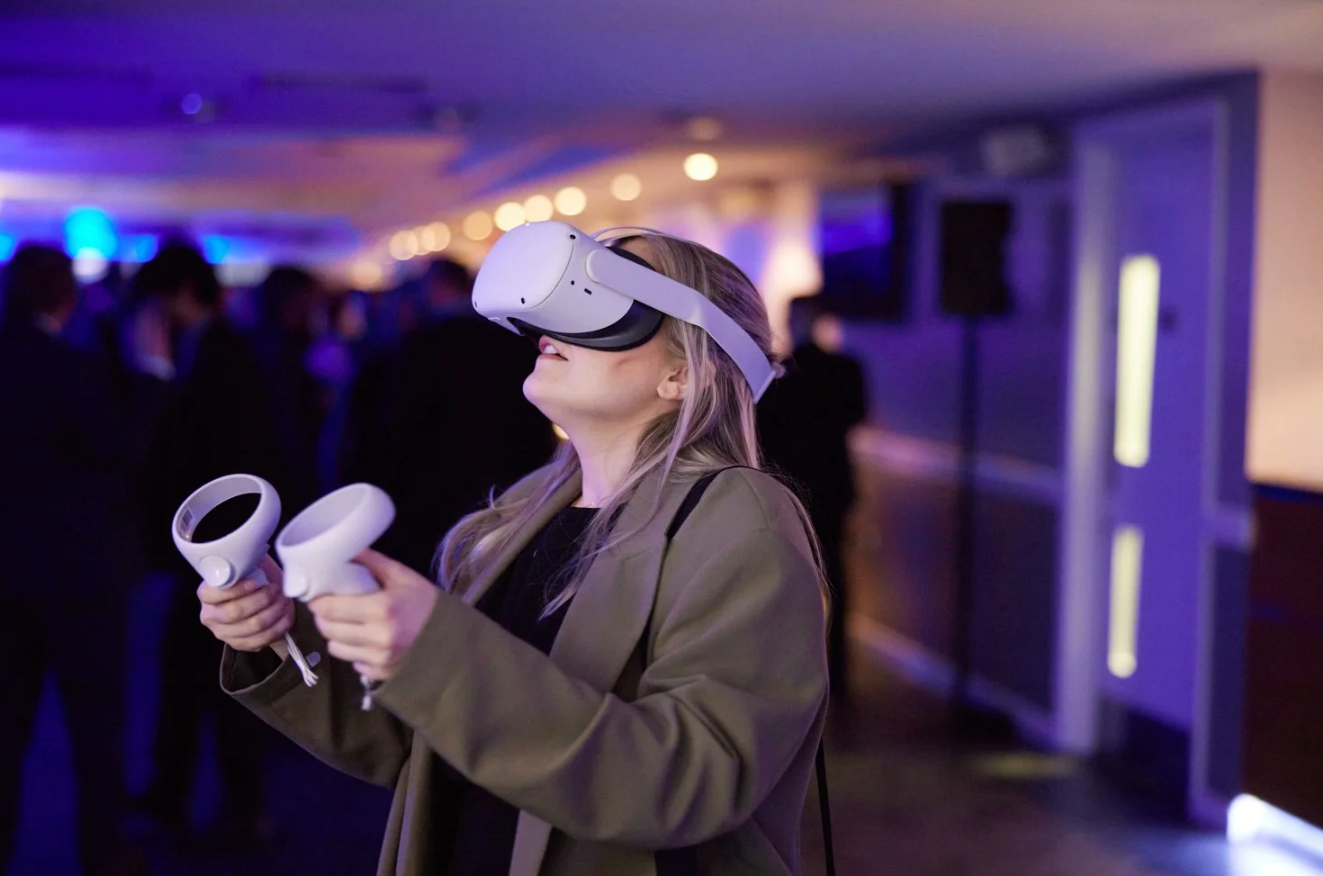 People in a dark room wearing VR headsets and moving around while experiencing virtual reality entertainment.