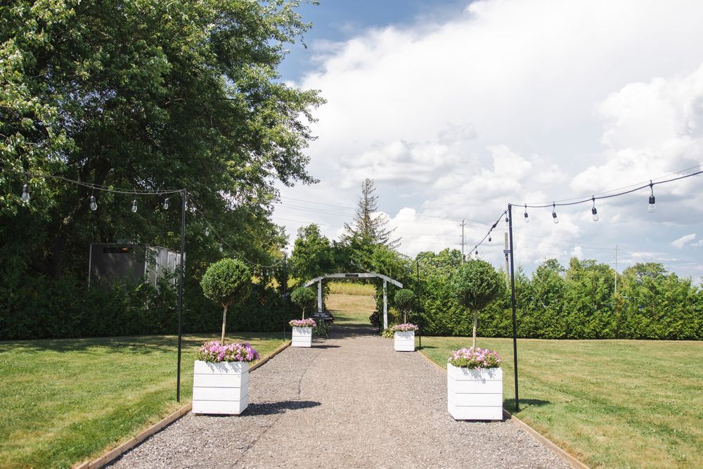 A panoramic view of a grassy hillside venue with string lights and white tents set up for an outdoor event.