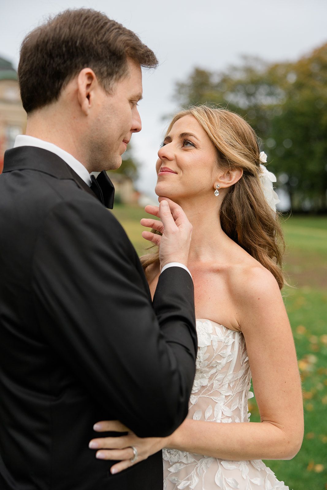 A romantic wedding couple shares an intimate moment together in a scenic outdoor setting with autumn foliage.