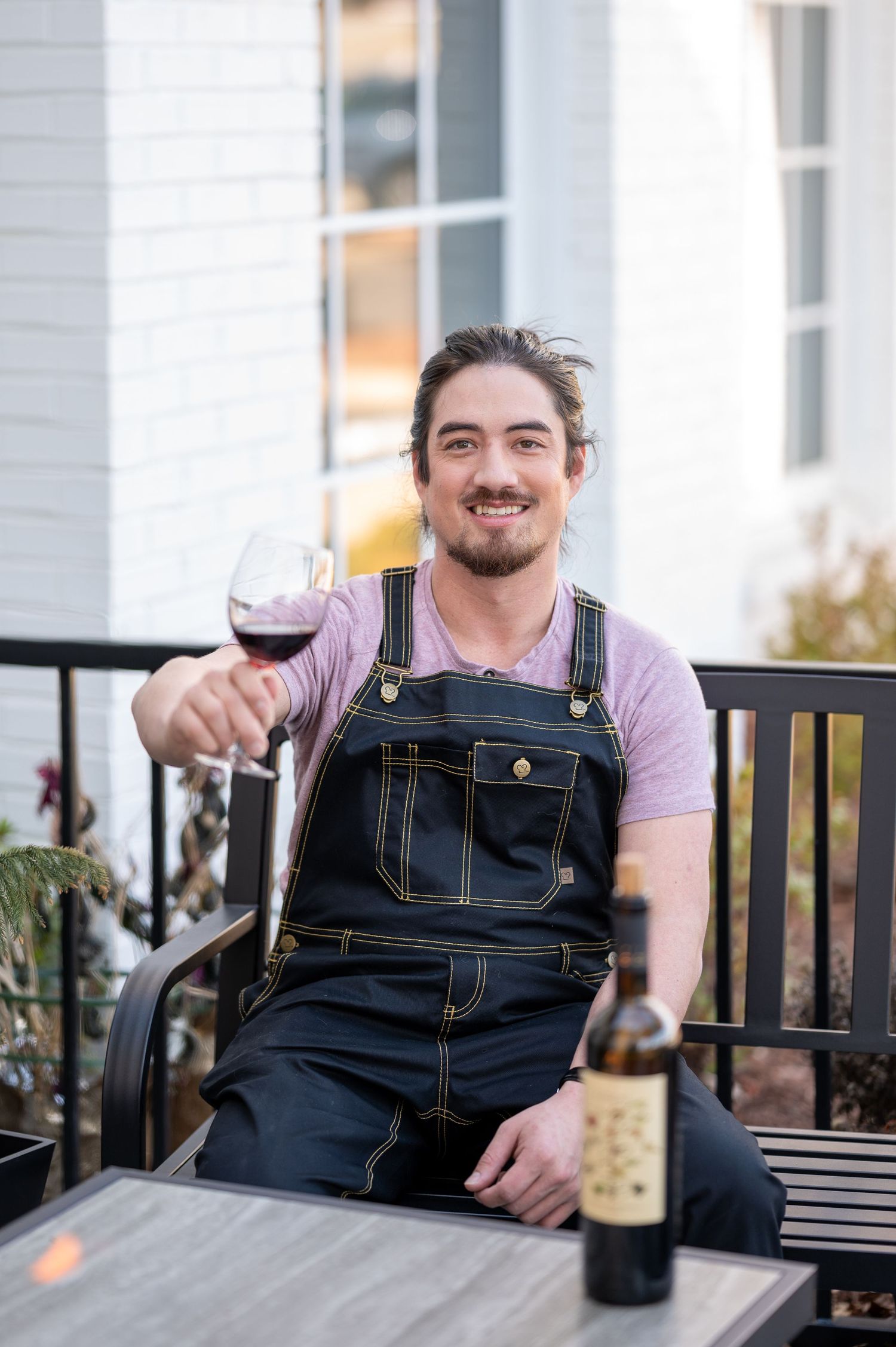 Person relaxing outdoors with wine glass on porch bench.